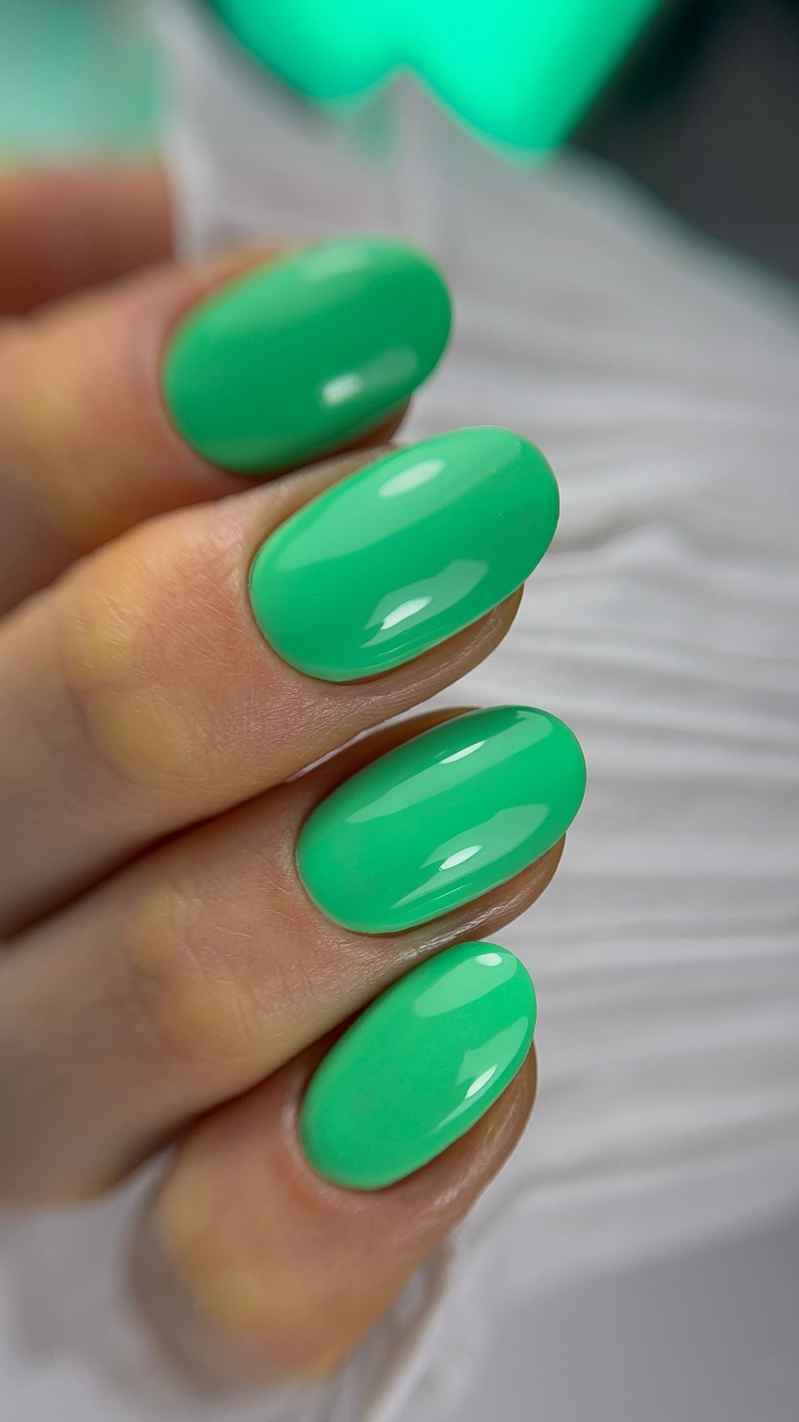 Pose du Gel Polish Palm vert jade sur ongles ovales courts, néon vert en arrière-plan