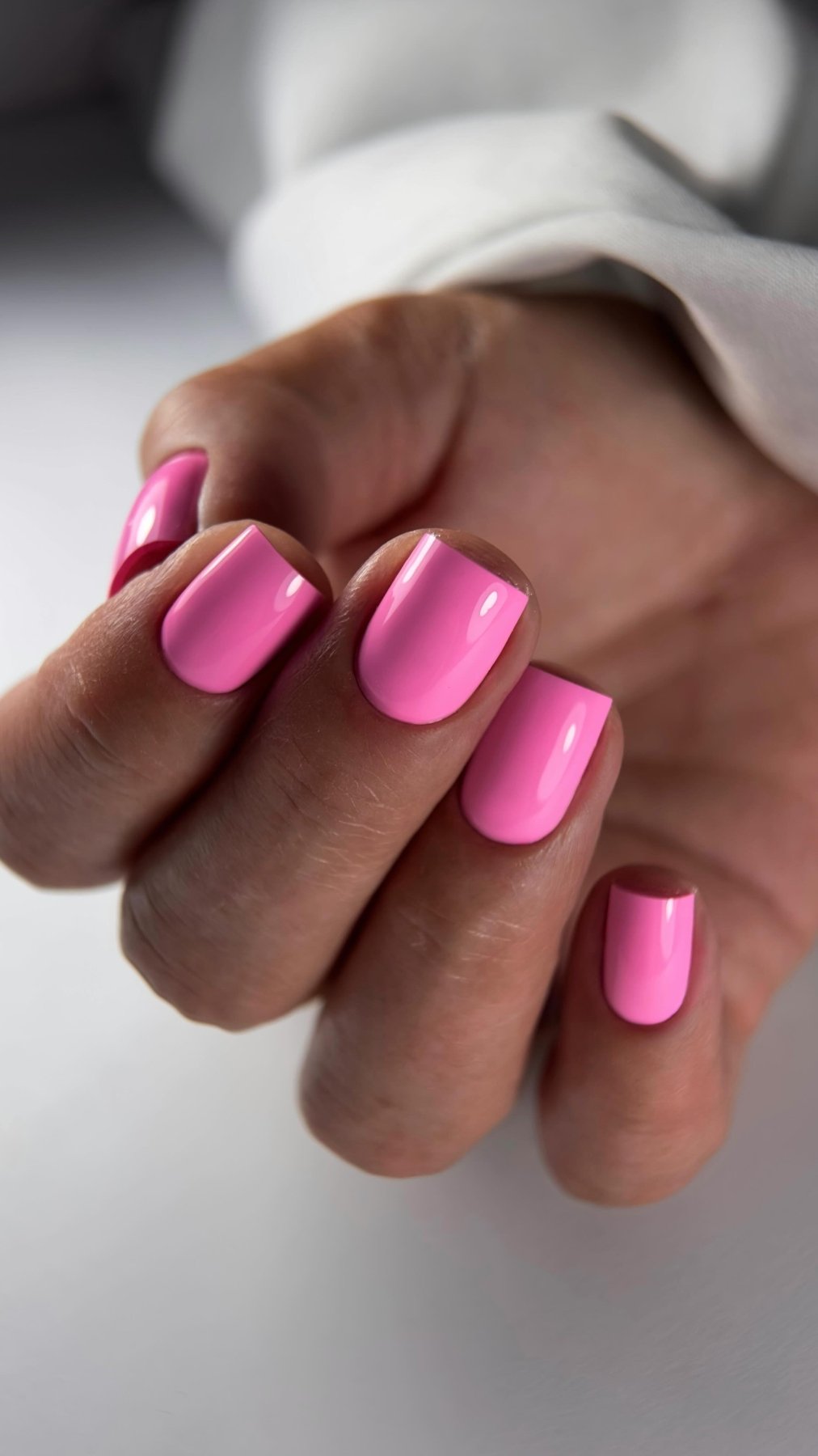 Gel Polish Bikini rose barbe à papa sur ongles carrés courts, main fermée et manche blanche