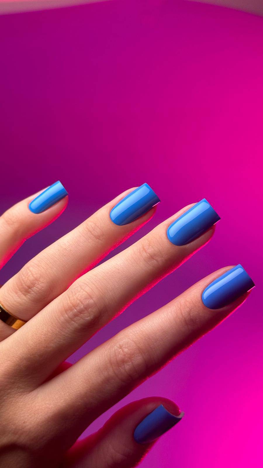 Pose du Gel Polish Friends bleu bleuet sur ongles carrés, fond rose fuchsia