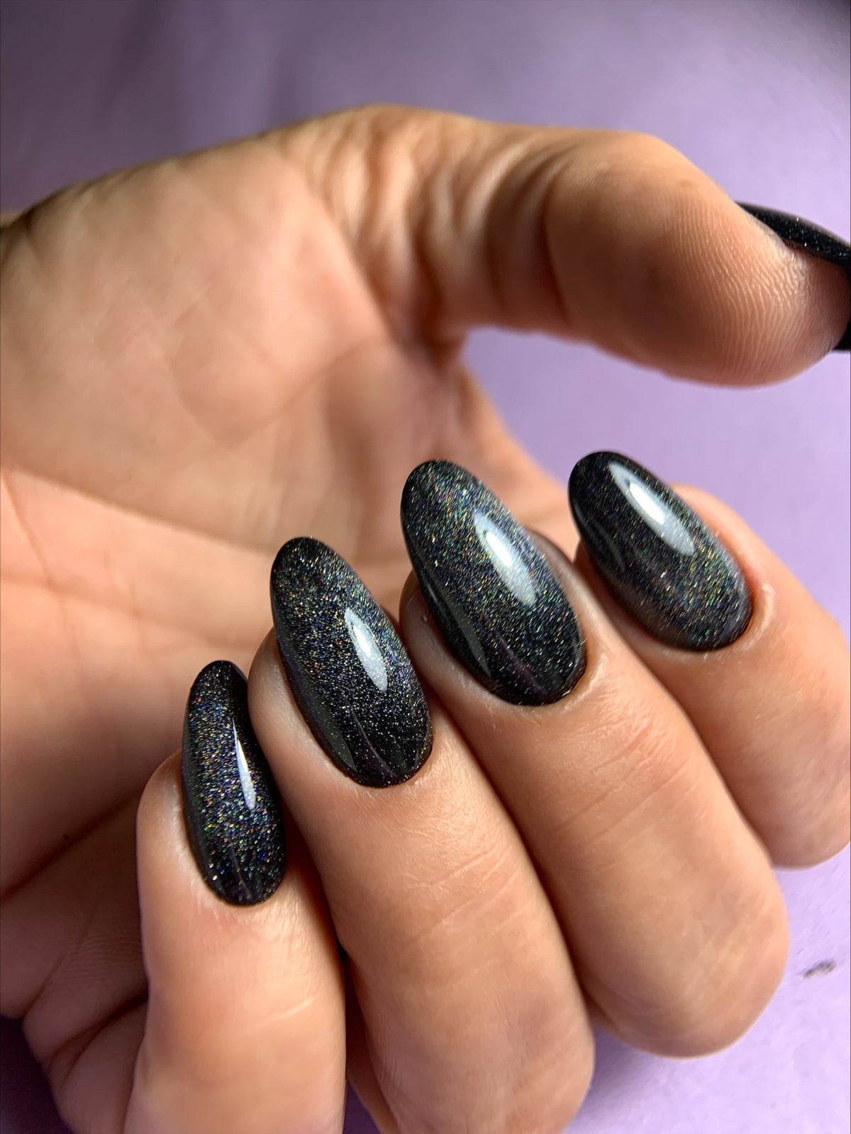 Pose du Gel Polish Smoke noir aux reflets holographiques sur ongles en amande