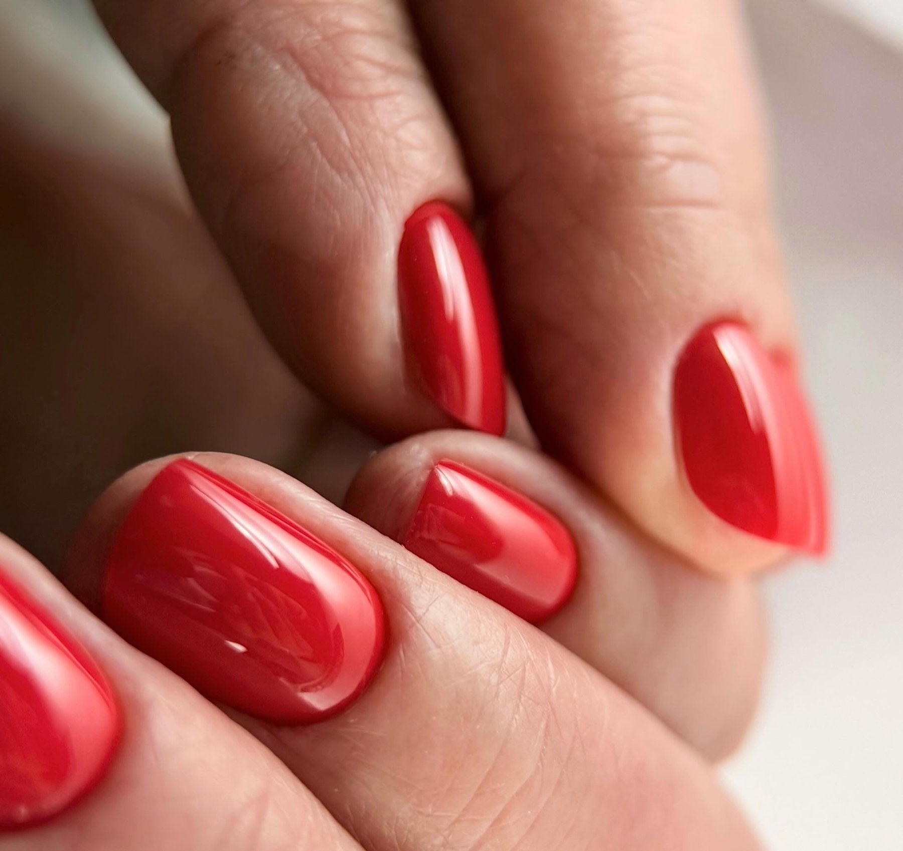 Pose du Gel Polish Candy Cane rouge cerise sur ongles courts ovales, finition brillante