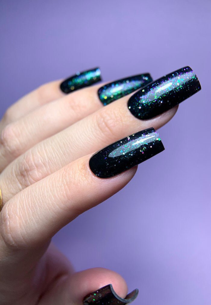 Gel Polish Army noir à paillettes vertes sur ongles carrés longs, fond lilas