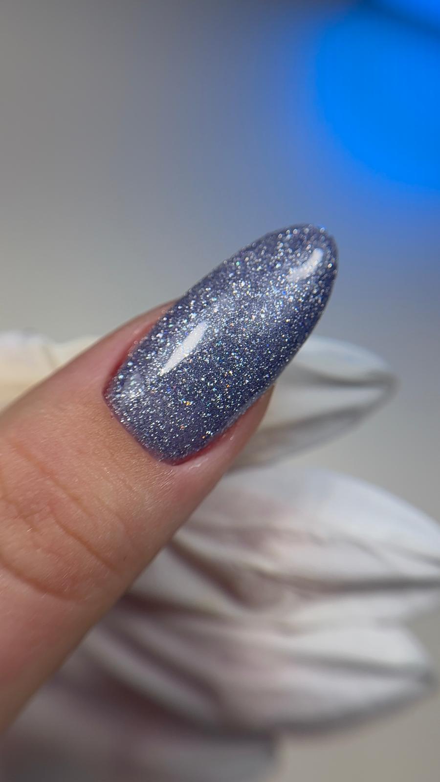 Gros plan du Gel Polish Aqua pailleté argent-bleu sur ongle en amande