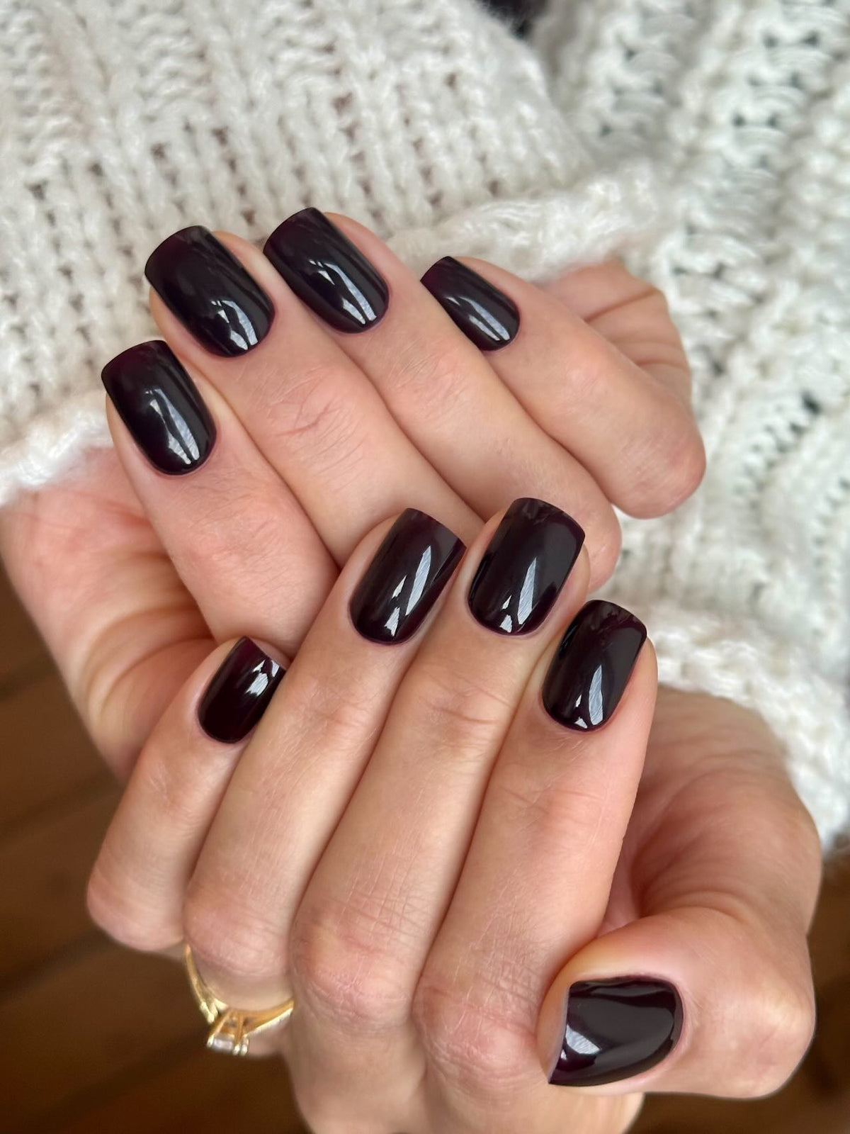 Gel Polish Robusta prune bordeaux sur ongles carrés, deux mains et pull blanc en maille