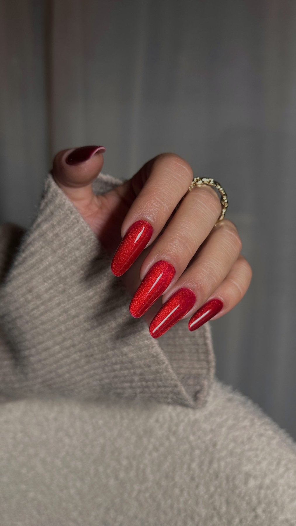 Pose du Gel Polish Cat Chili rouge éclatant sur ongles longs ballerine, main sur pull beige