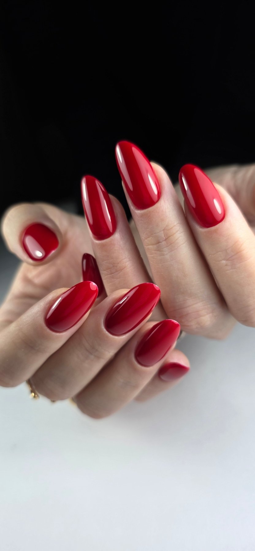 Vernis semi-permanent rouge rubis Gel Polish Ruby sur ongles longs en amande, fond noir
