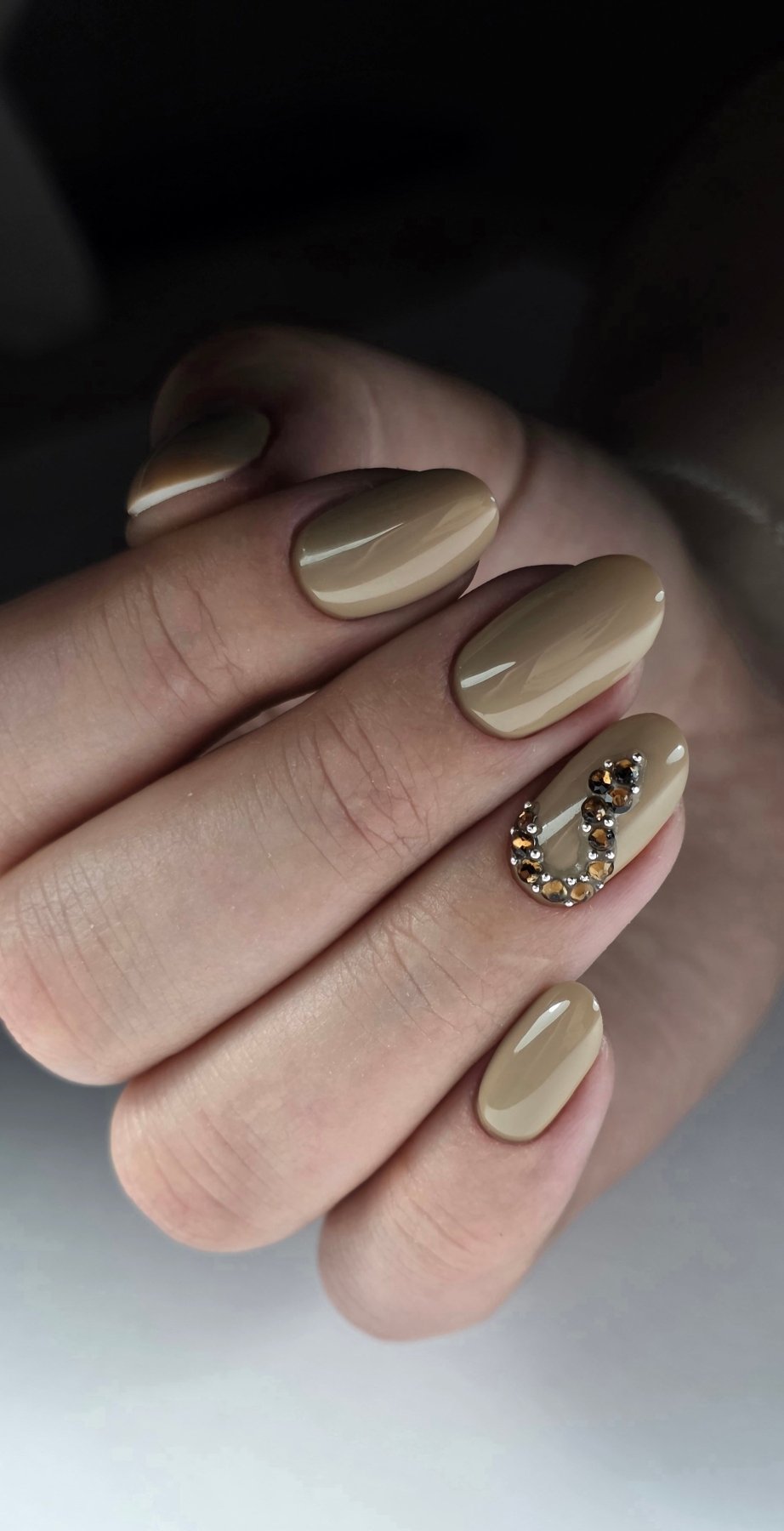 Pose du Gel Polish Cream beige nude sur ongles ovales, un ongle orné de strass ambrés