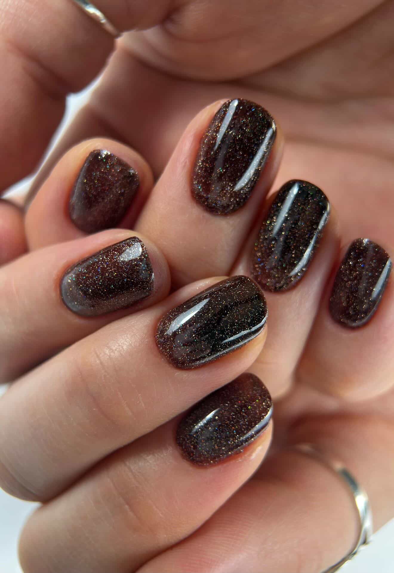 Pose du Gel Polish Brownie chocolat pailleté sur ongles courts arrondis, bagues argentées