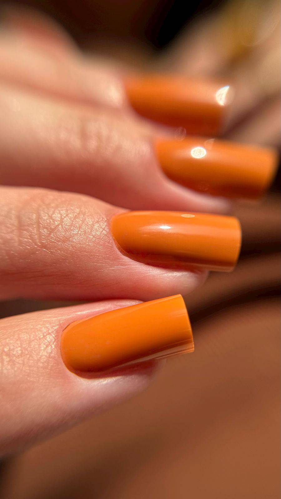 Gros plan du Gel Polish Hunter orange caramel sur ongles carrés longs brillants