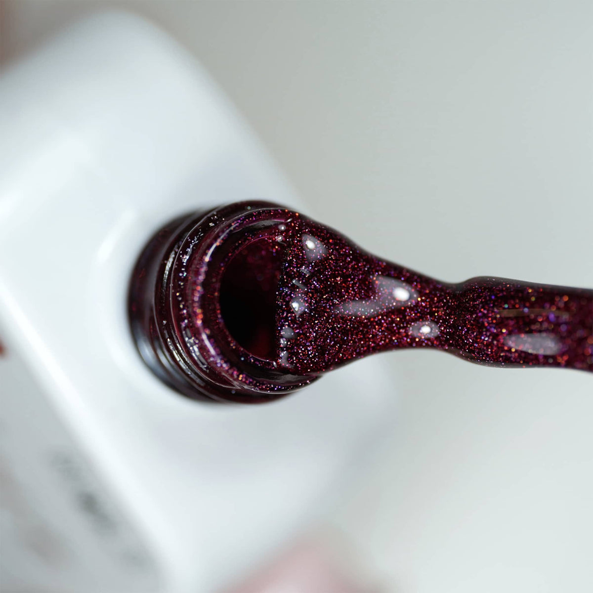 Pinceau et goulot du Gel Polish Love, texture bordeaux dense aux micro-paillettes