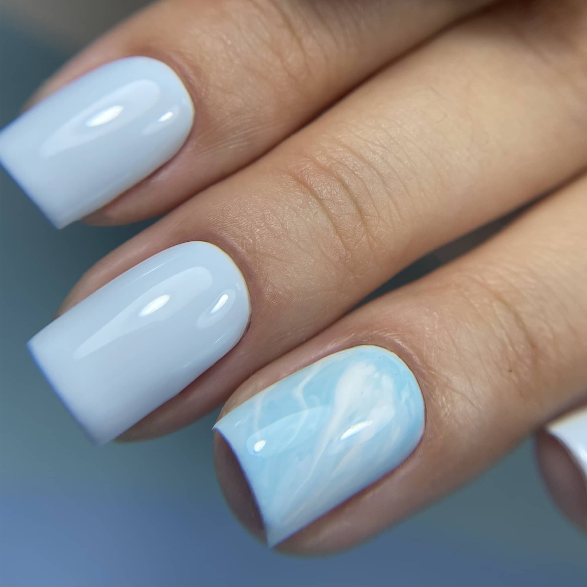 Pose du Gel Polish Angel bleu ciel sur ongles carrés courts avec accent marbré nuage