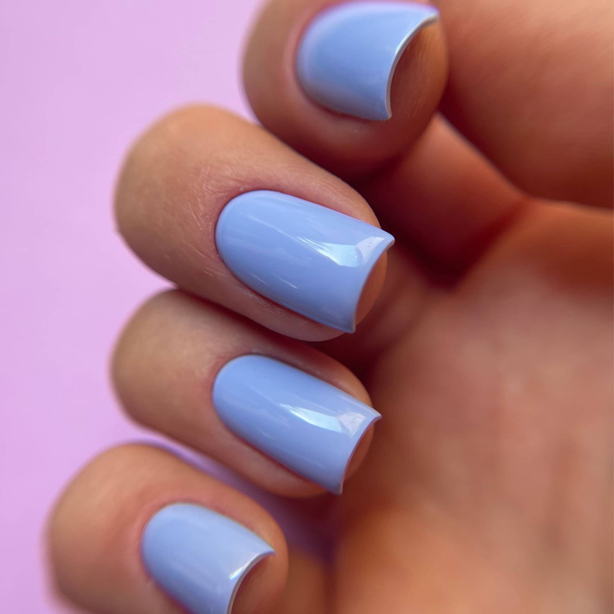 Pose du Gel Polish Bae violet lavande sur ongles carrés courts, fond rose pastel
