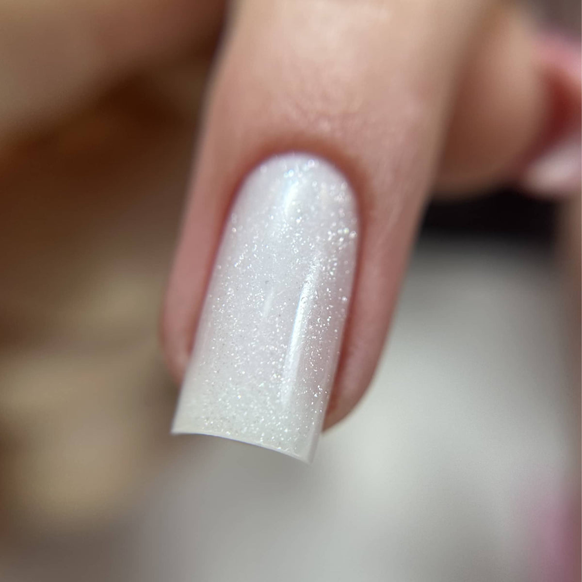 Macro d'un ongle carré au gel Solid fiber milky shine montrant les micro-paillettes