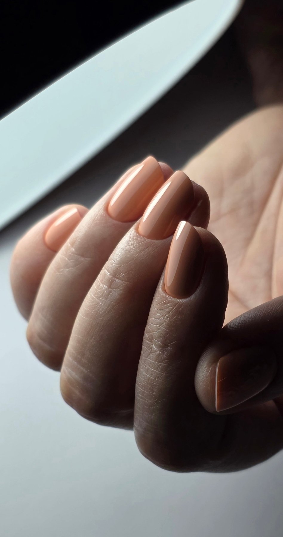 Gel Polish Marry me abricot sur ongles carrés courts, lumière rasante sur la main