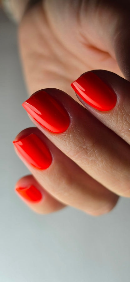 Gel Polish Sol do amor orange feu sur ongles carrés courts, main repliée en gros plan