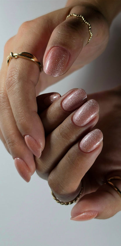 Gel Polish Harly rose nude pailleté sur ongles ovales courts, deux mains et bagues dorées