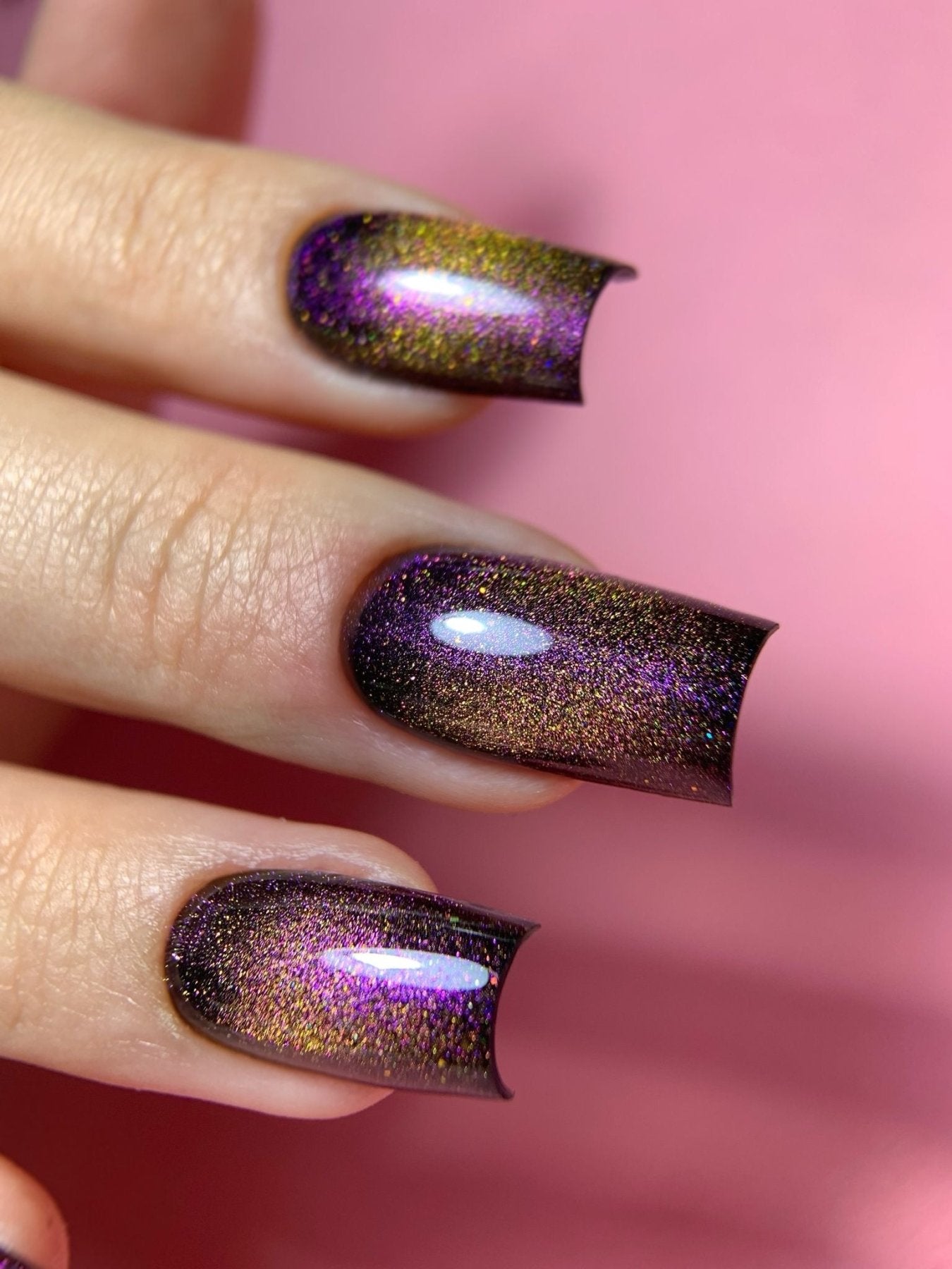 Gros plan de l'effet cat eye du Gel Polish Boréal, reflets violets et dorés sur fond rose