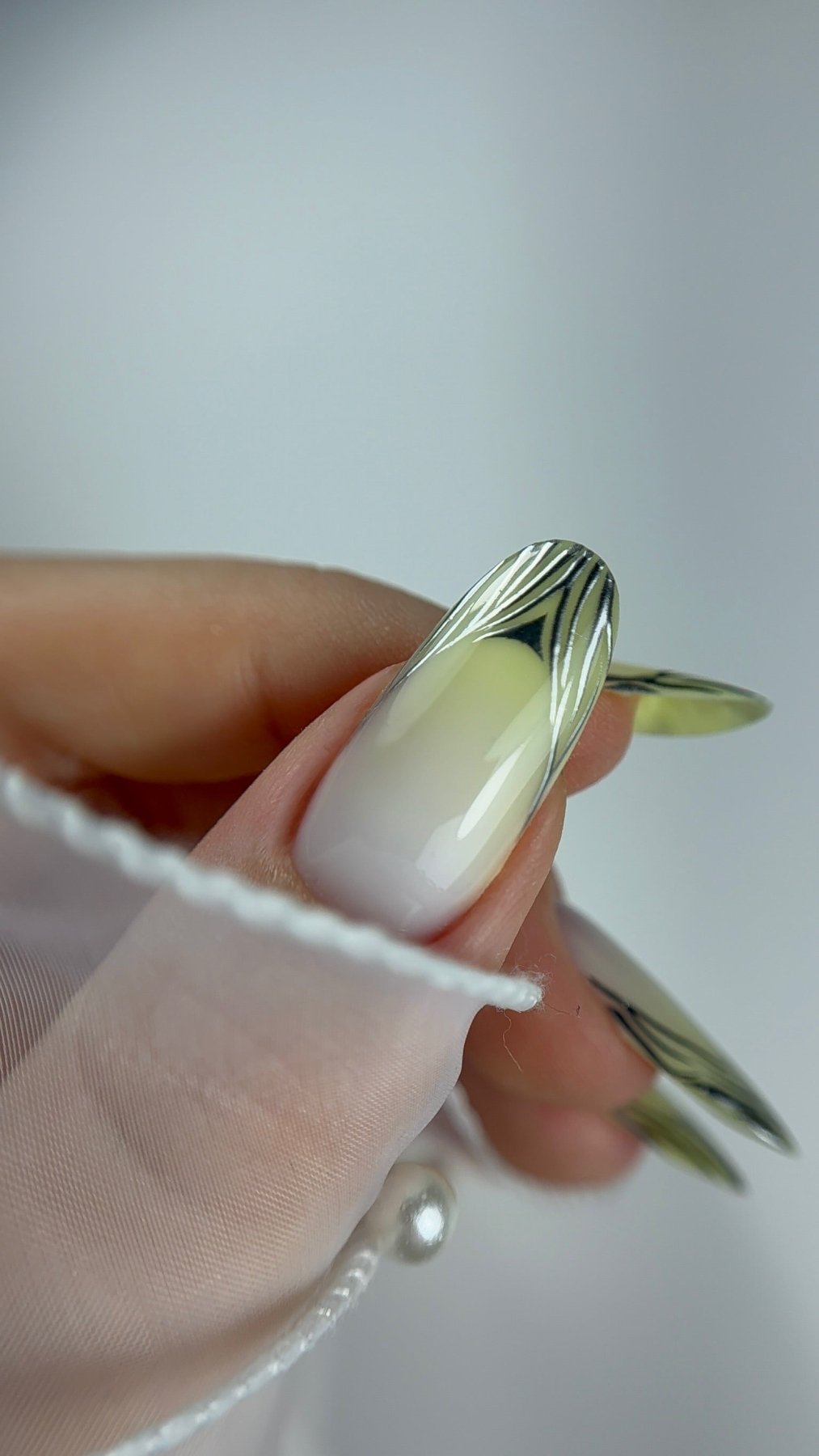 Macro d'un ongle amande : traits chrome Liquide Silver sur une base blanc laiteux
