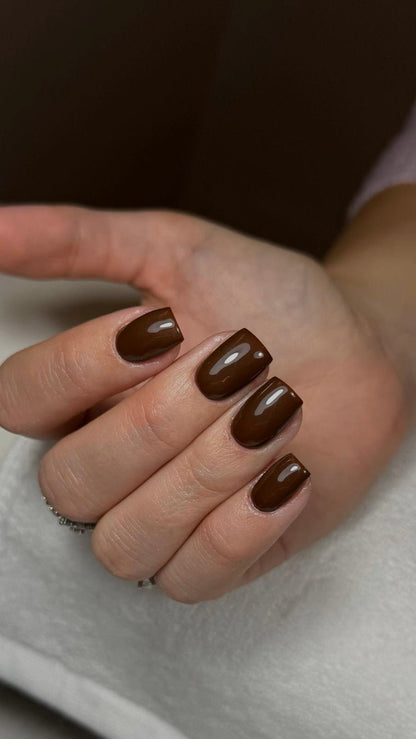 Pose du Gel Polish Espresso chocolat sur ongles carrés, main posée sur une serviette blanche