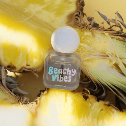 Eau hydratante cuticules Beachy Vibes posée sur un ananas ouvert, fond jaune ensoleillé