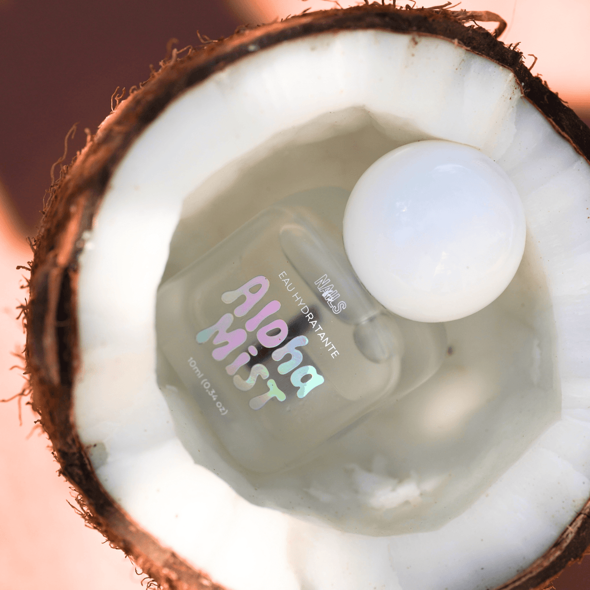 Eau hydratante cuticules Aloha Mist posée dans une noix de coco fraîchement ouverte