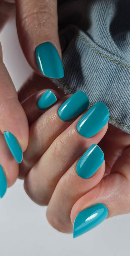 Pose du Gel Polish Ipanema bleu canard sur ongles courts arrondis, tenue en jean