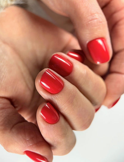 Gel Polish Candy Cane rouge cerise sur ongles courts carrés, gros plan sur une main fermée