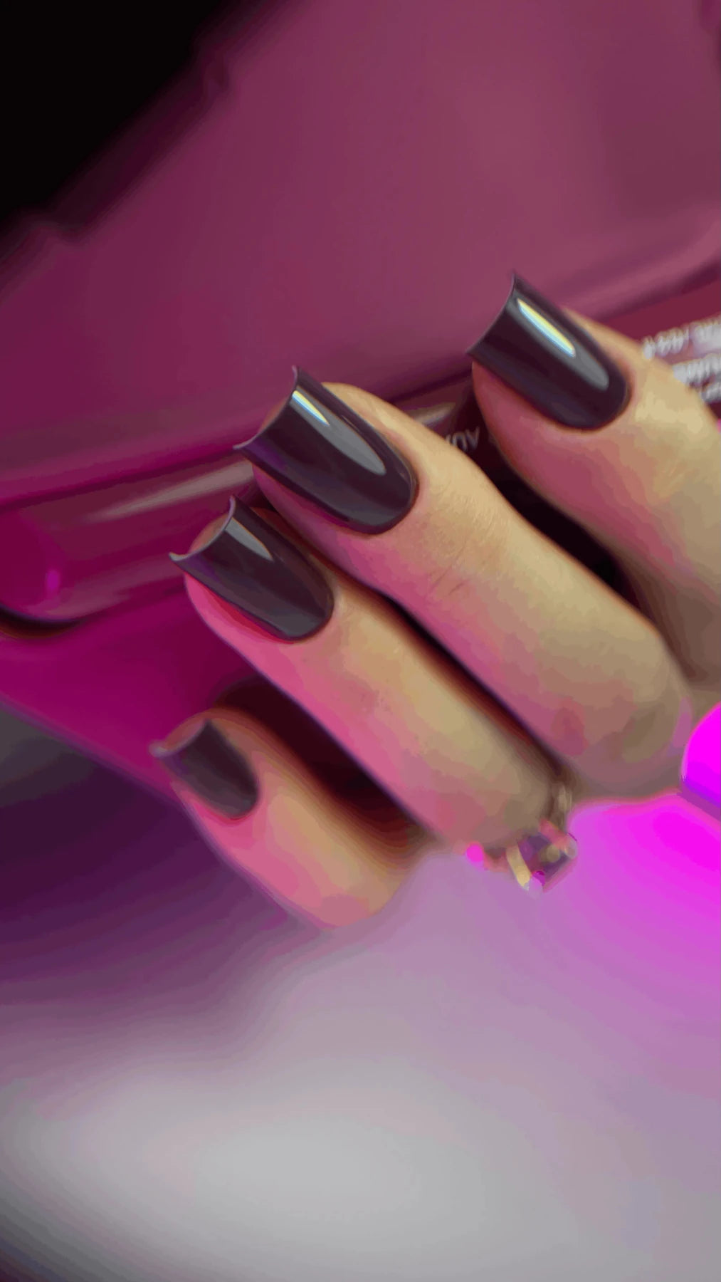Pose du Gel Polish Cake prune foncé sur ongles carrés longs, sous lumière néon rose