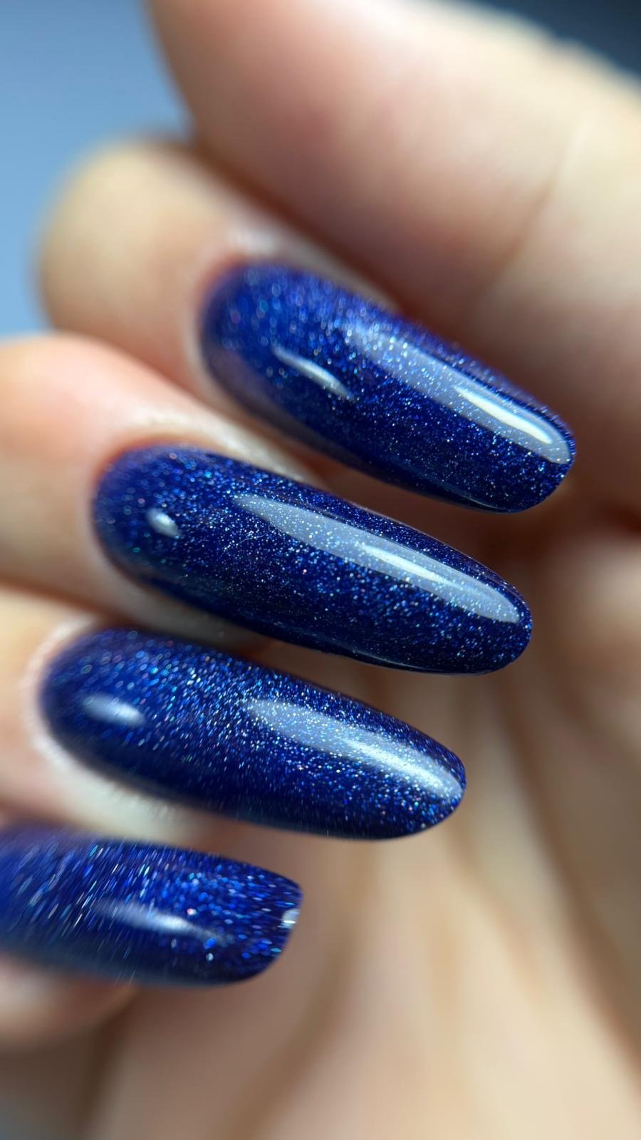 Gros plan de la pose Artic Blue, paillettes holographiques sur fond bleu nuit