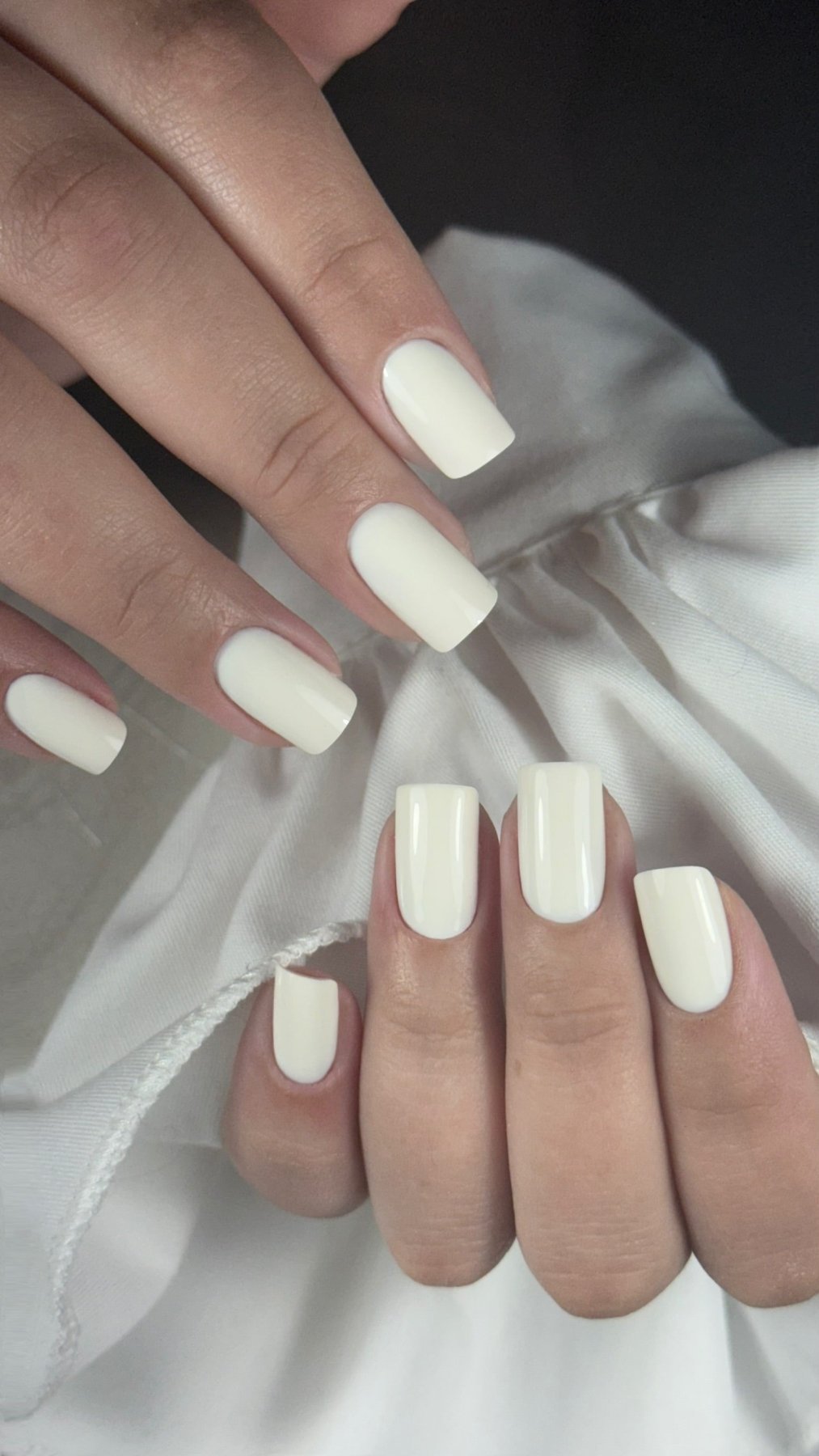 Pose du Gel Polish Yes blanc cassé sur ongles carrés, tissu blanc en fond