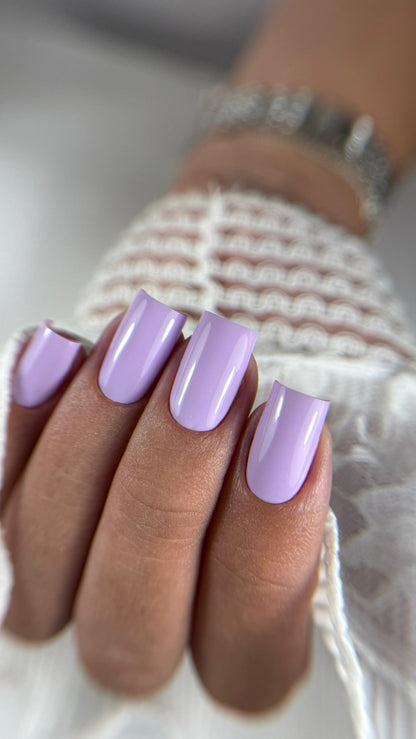 Pose du Gel Polish Butterfly lilas pastel sur ongles carrés longs, pull blanc et bracelet argenté