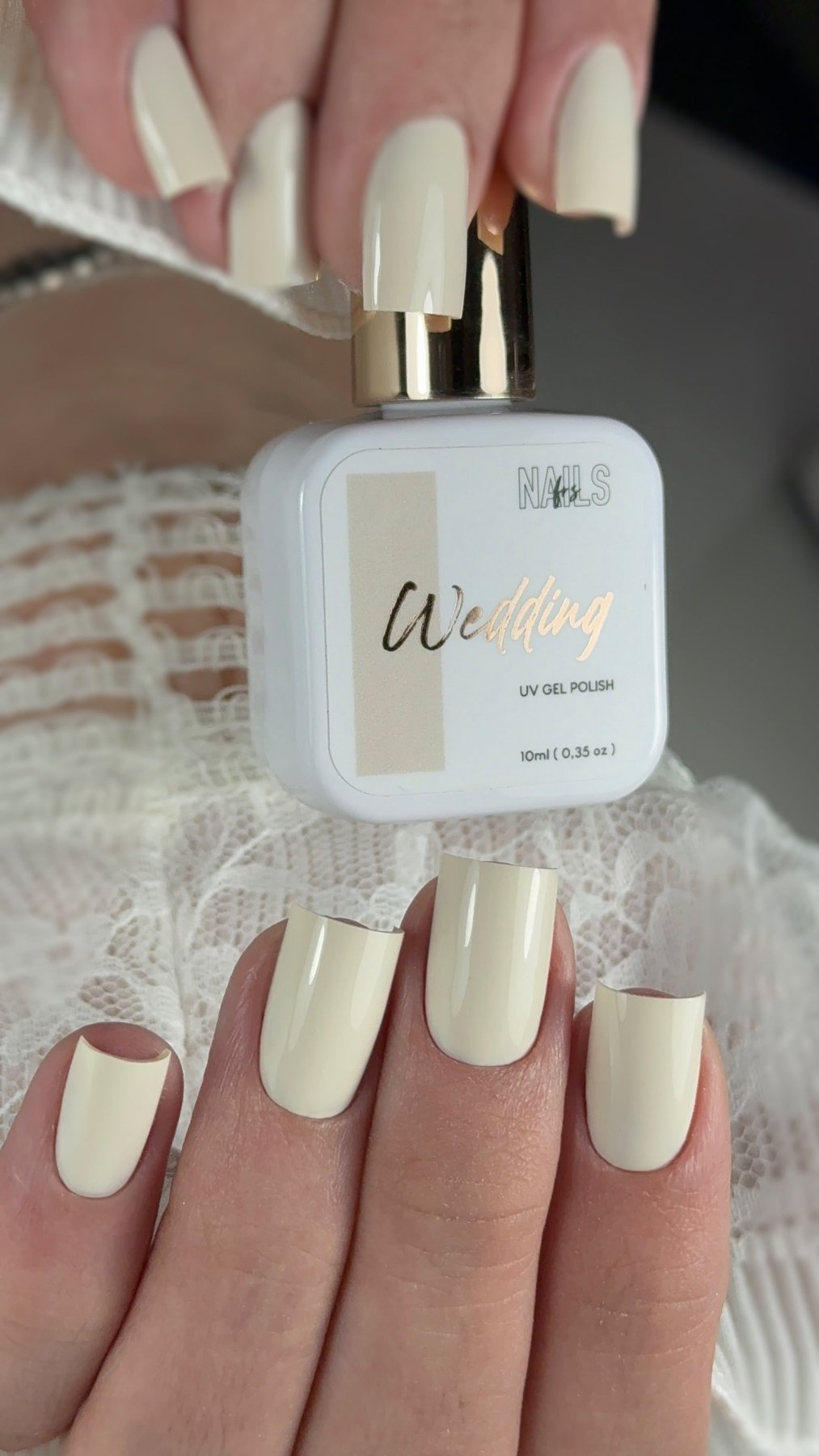 Flacon Gel Polish Wedding tenu en main avec une manucure ivoire assortie sur ongles carrés