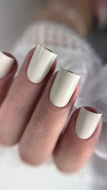 Gros plan de la pose Gel Polish Wedding blanc ivoire sur ongles carrés, dentelle en fond
