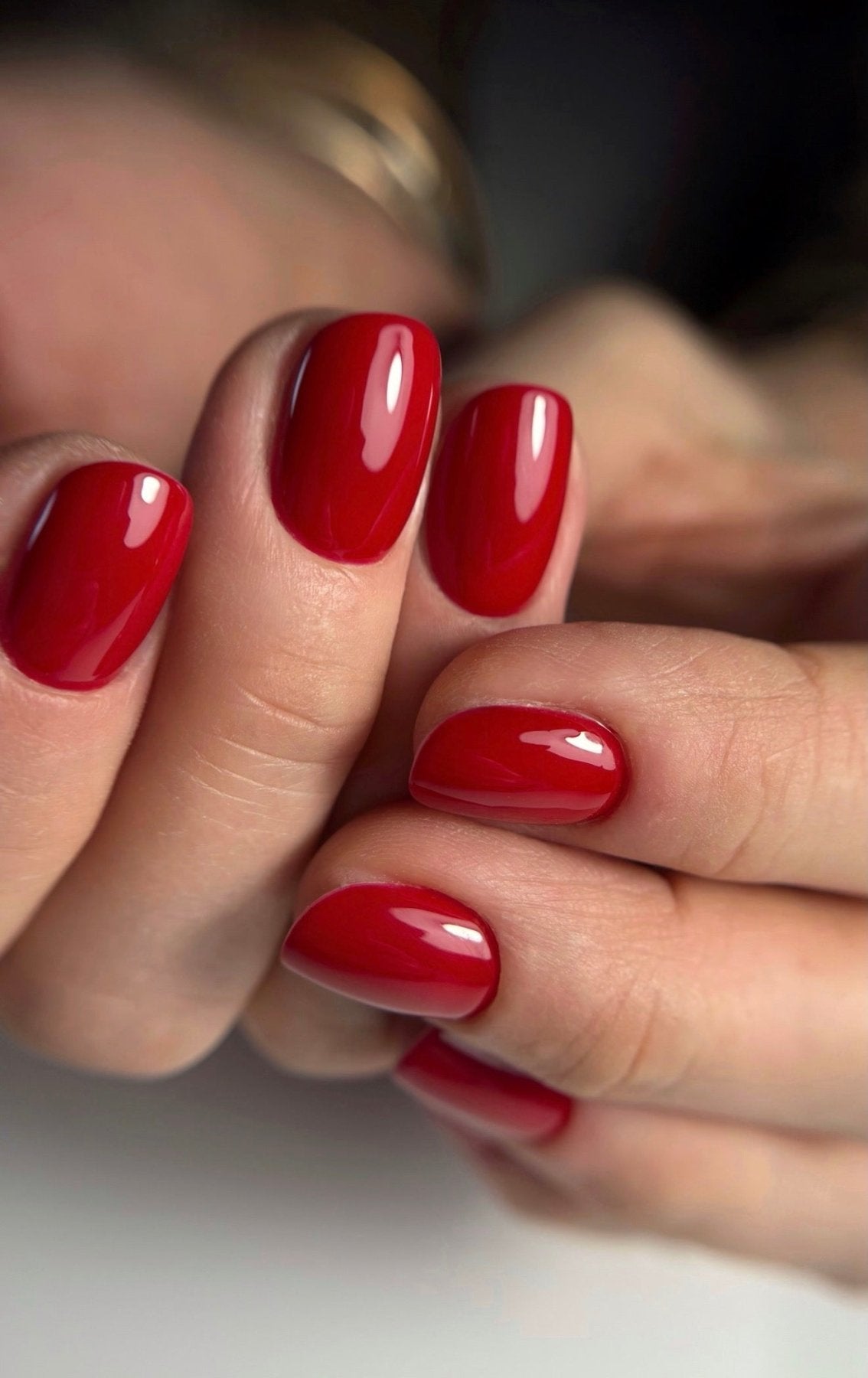 Pose du Gel Polish Ruby rouge rubis sur ongles courts arrondis, mains croisées