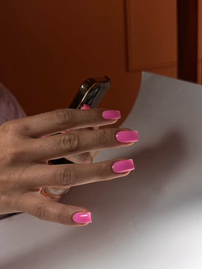 Ongles carrés au gel Easy gel Rio, rose fuchsia vif, main tenant un téléphone