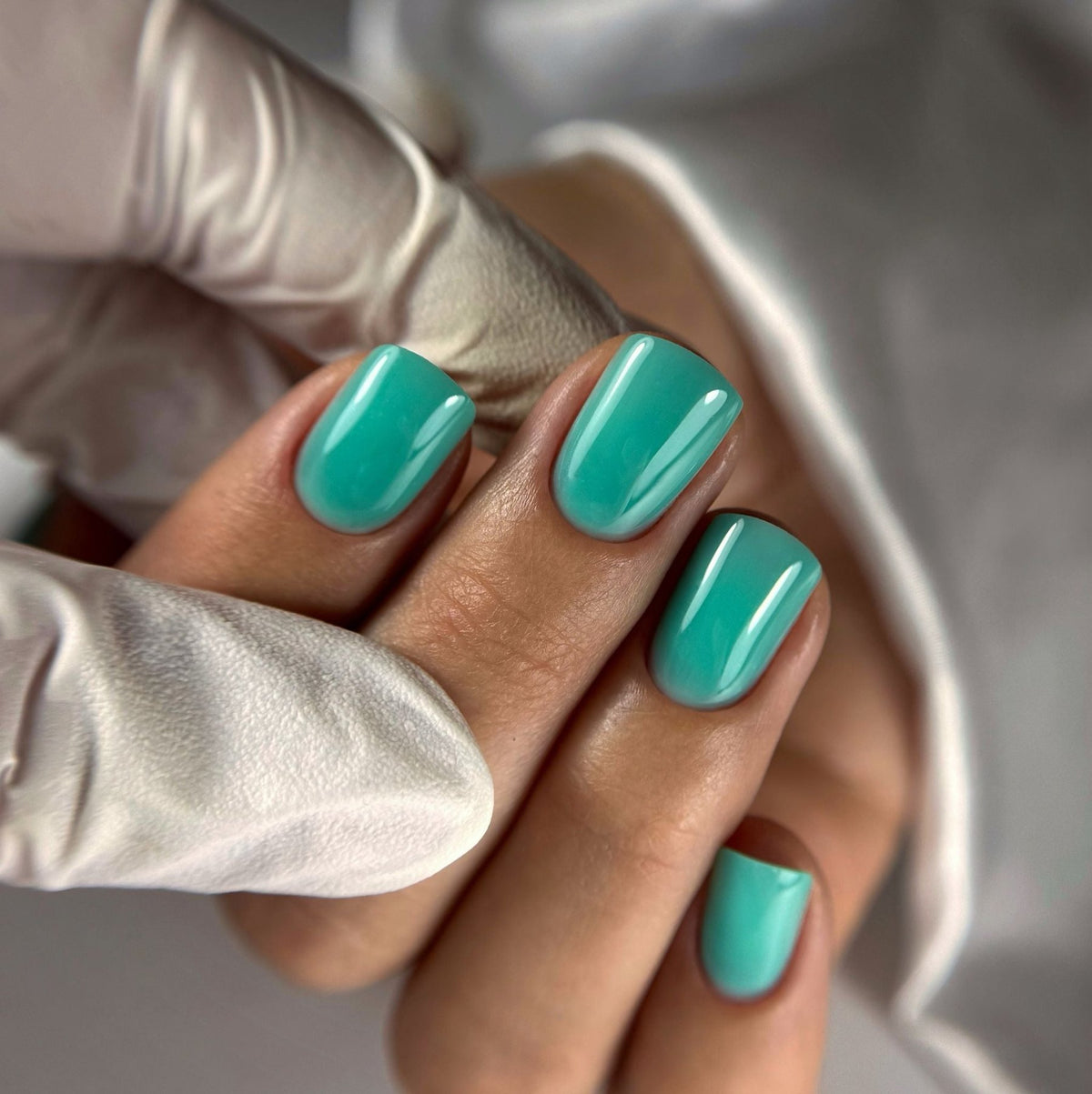 Pose de la Cloud base Noa turquoise sur ongles carrés courts, rendu couvrant brillant
