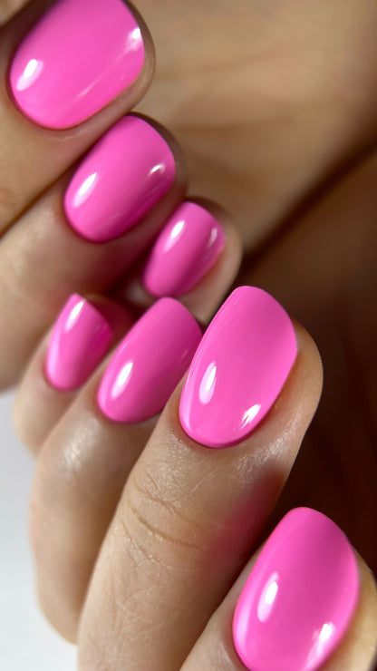 Pose du Gel Polish Spring rose bonbon vif sur ongles ovales courts, gros plan brillant
