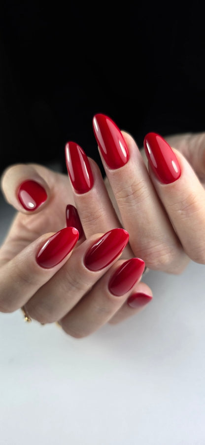 Vernis semi-permanent rouge rubis Gel Polish Ruby sur ongles longs en amande, fond noir