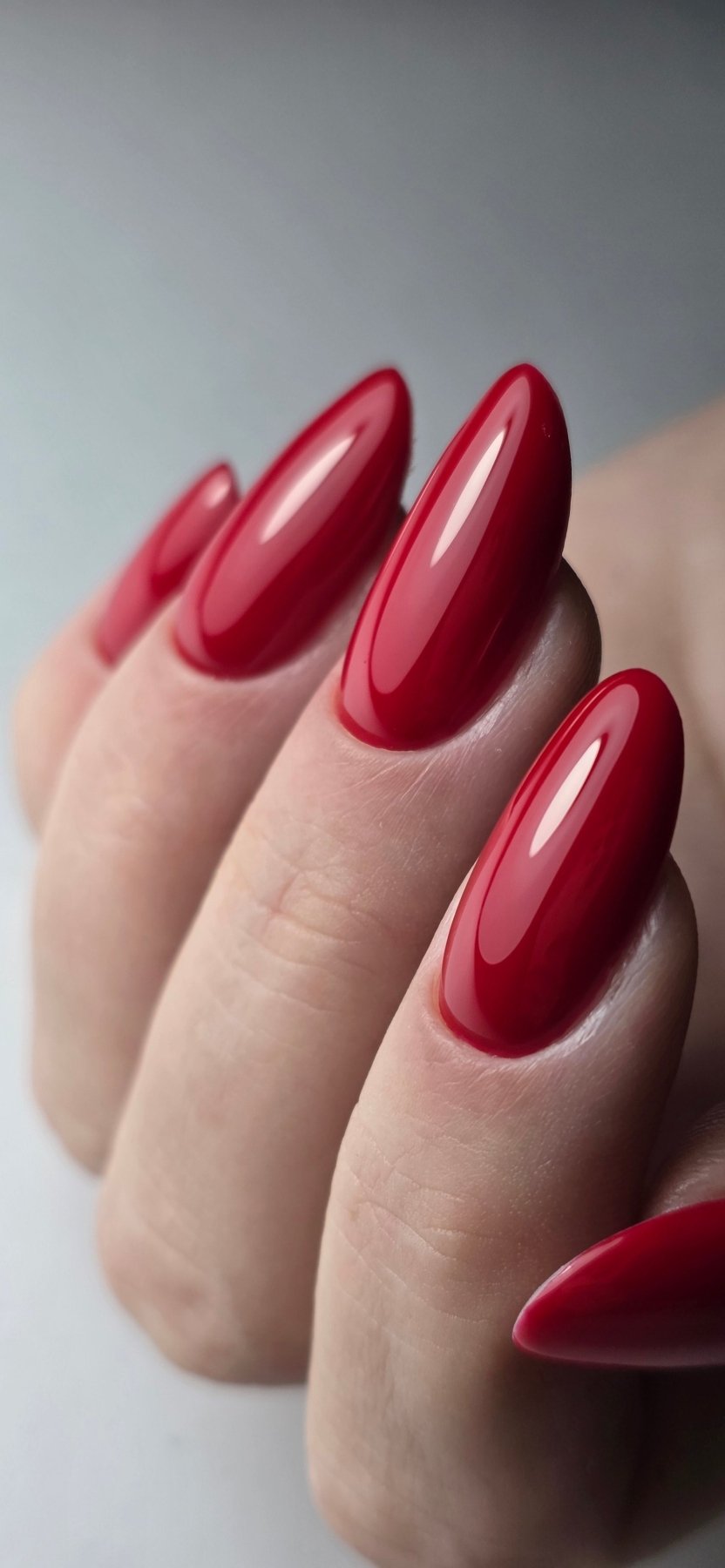 Gros plan du Gel Polish Ruby rouge rubis brillant sur ongles longs en amande