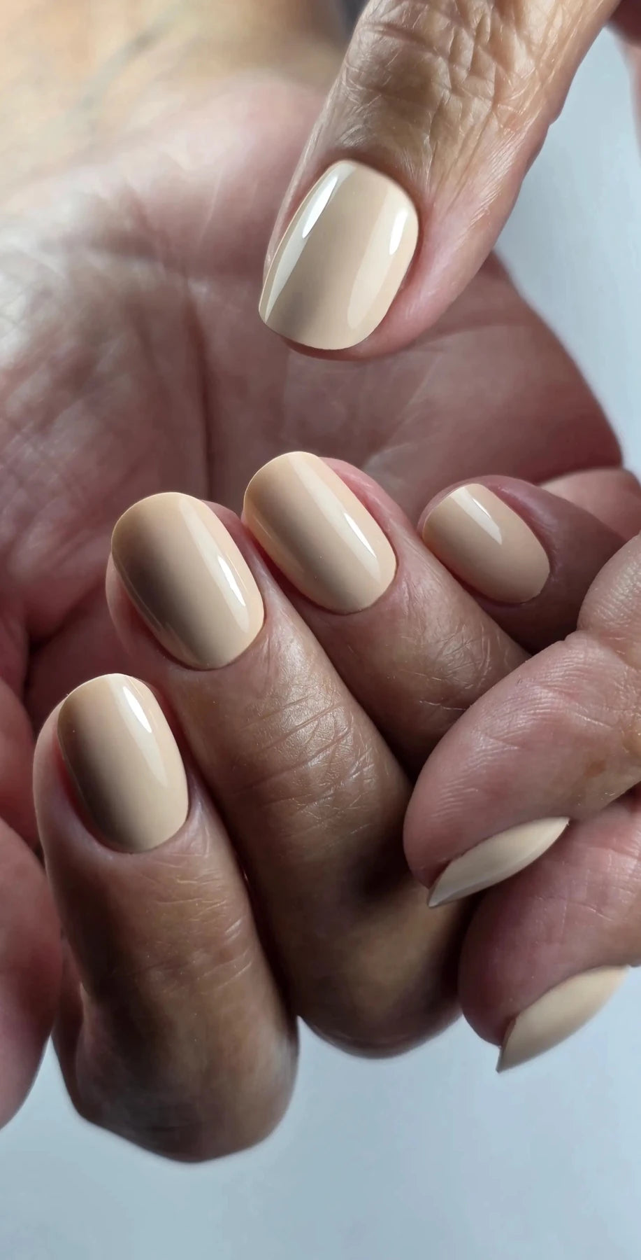 Deux mains aux ongles courts arrondis posés en Gel Polish Ceremony beige nude