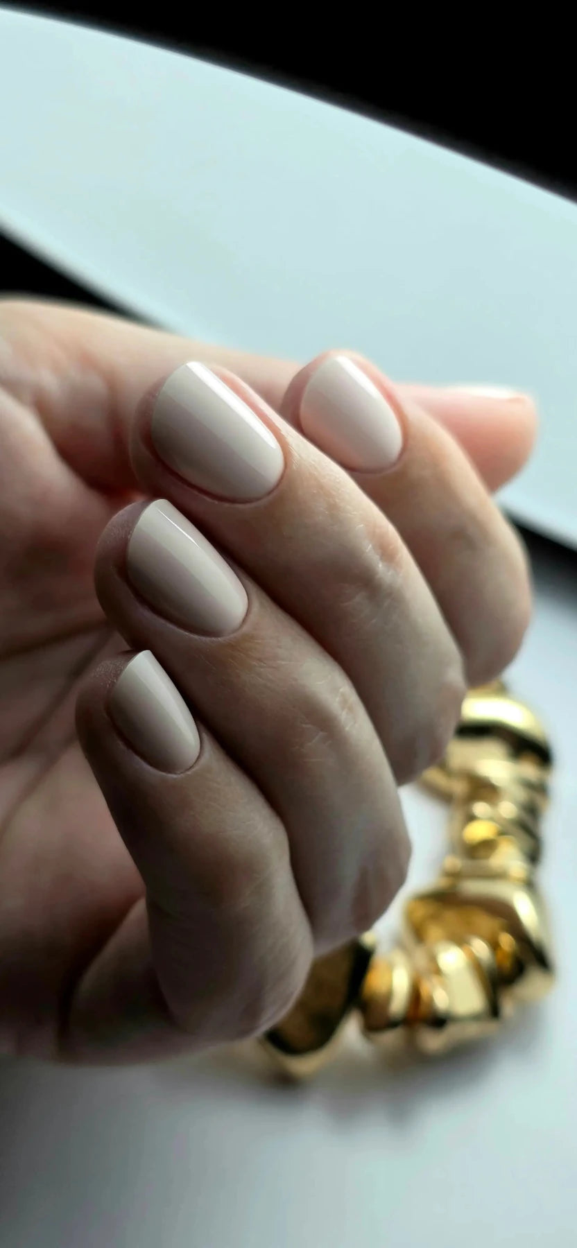 Gel Polish Bride rose ivoire sur ongles ovales courts, main portant un bracelet doré