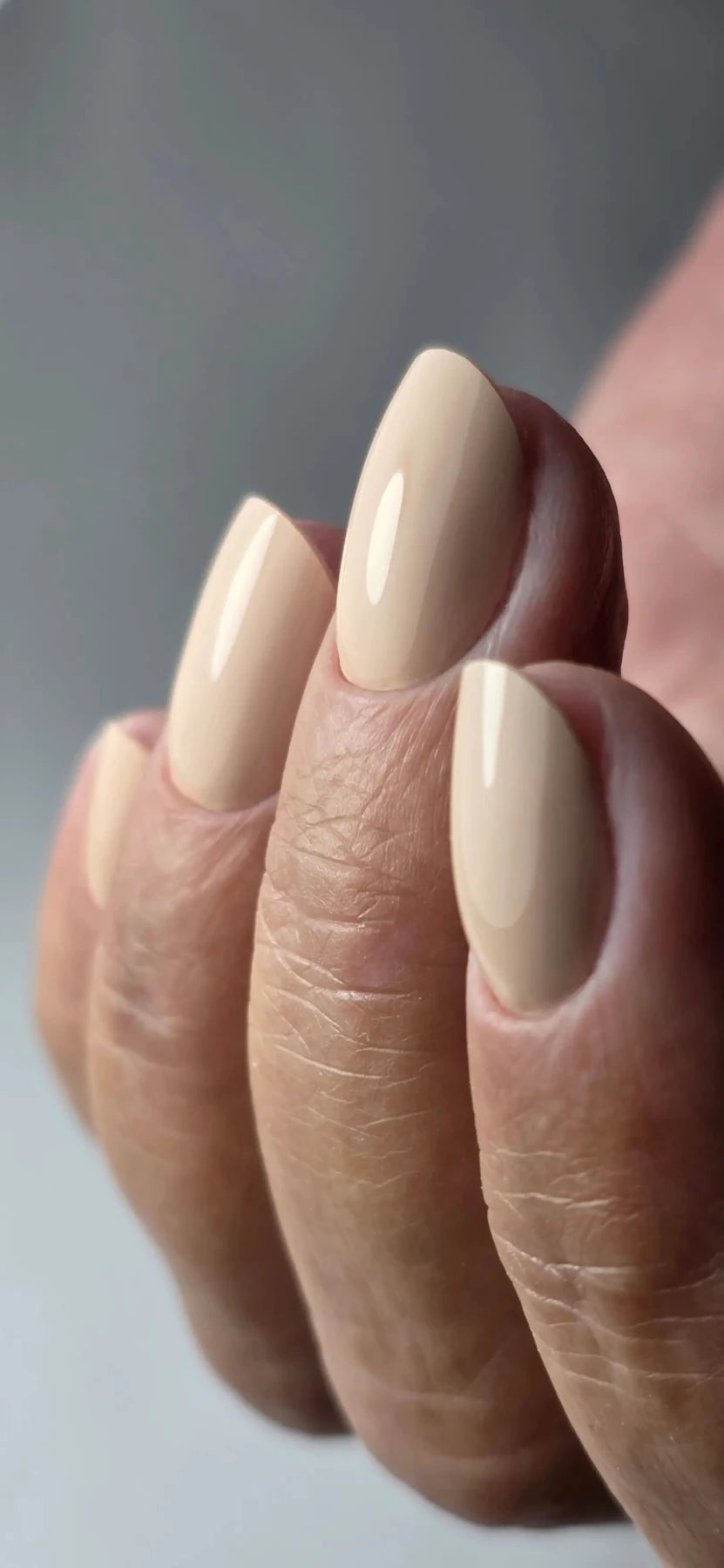 Gel Polish Ceremony nude sable posé sur ongles en amande, gros plan sur la brillance