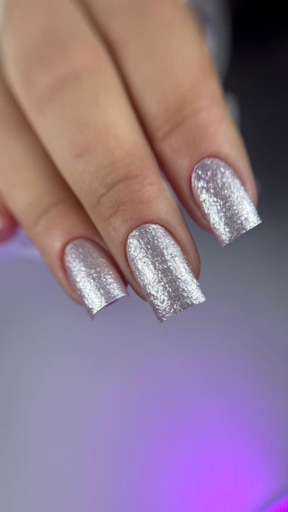 Gros plan d'ongles carrés en Ocean Crystal 01, effet feuille métallisée rose argenté