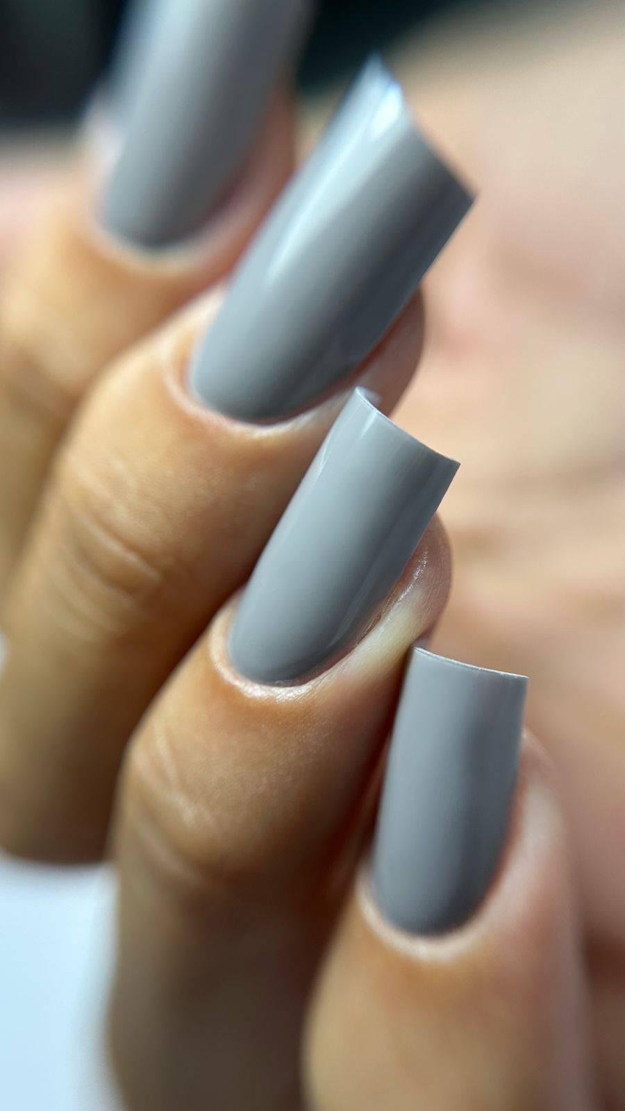 Gros plan de la pose Gel Polish Sauvage gris taupe sur ongles carrés longs