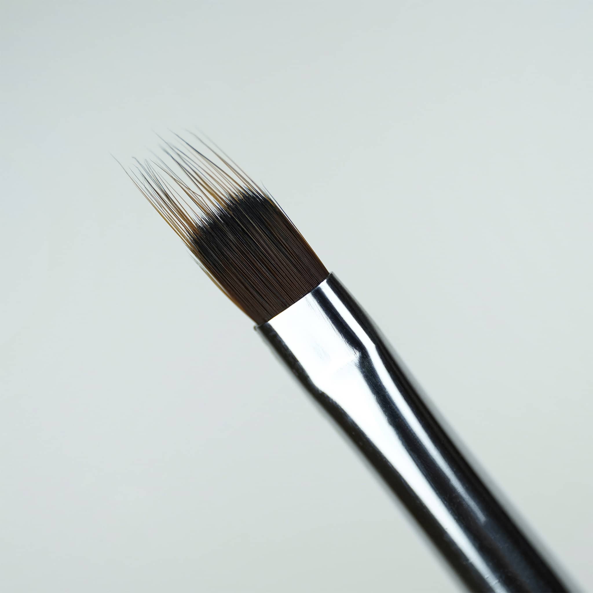 Tête plate à poils dentelés du Pinceau ombré, virole argentée et manche noir, en gros plan