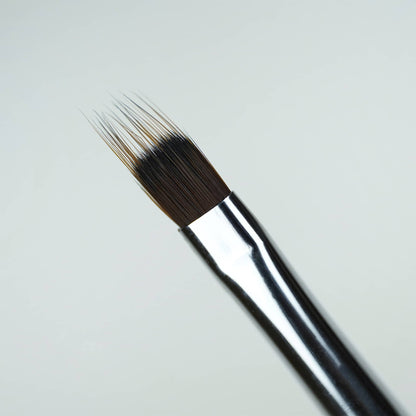 Tête plate à poils dentelés du Pinceau ombré, virole argentée et manche noir, en gros plan
